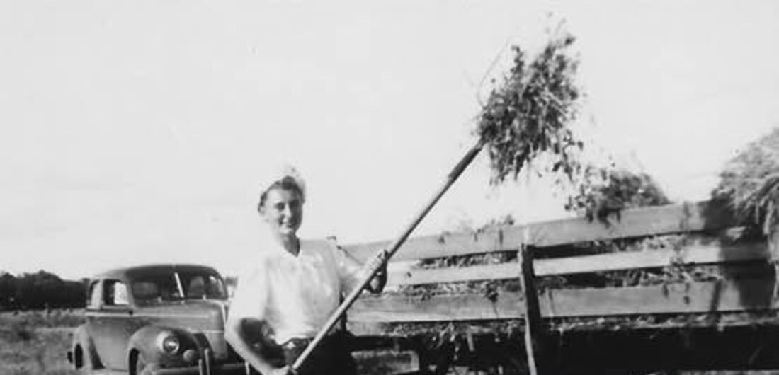 Mildred as a young woman pitching hay onto a wagon on the family farm